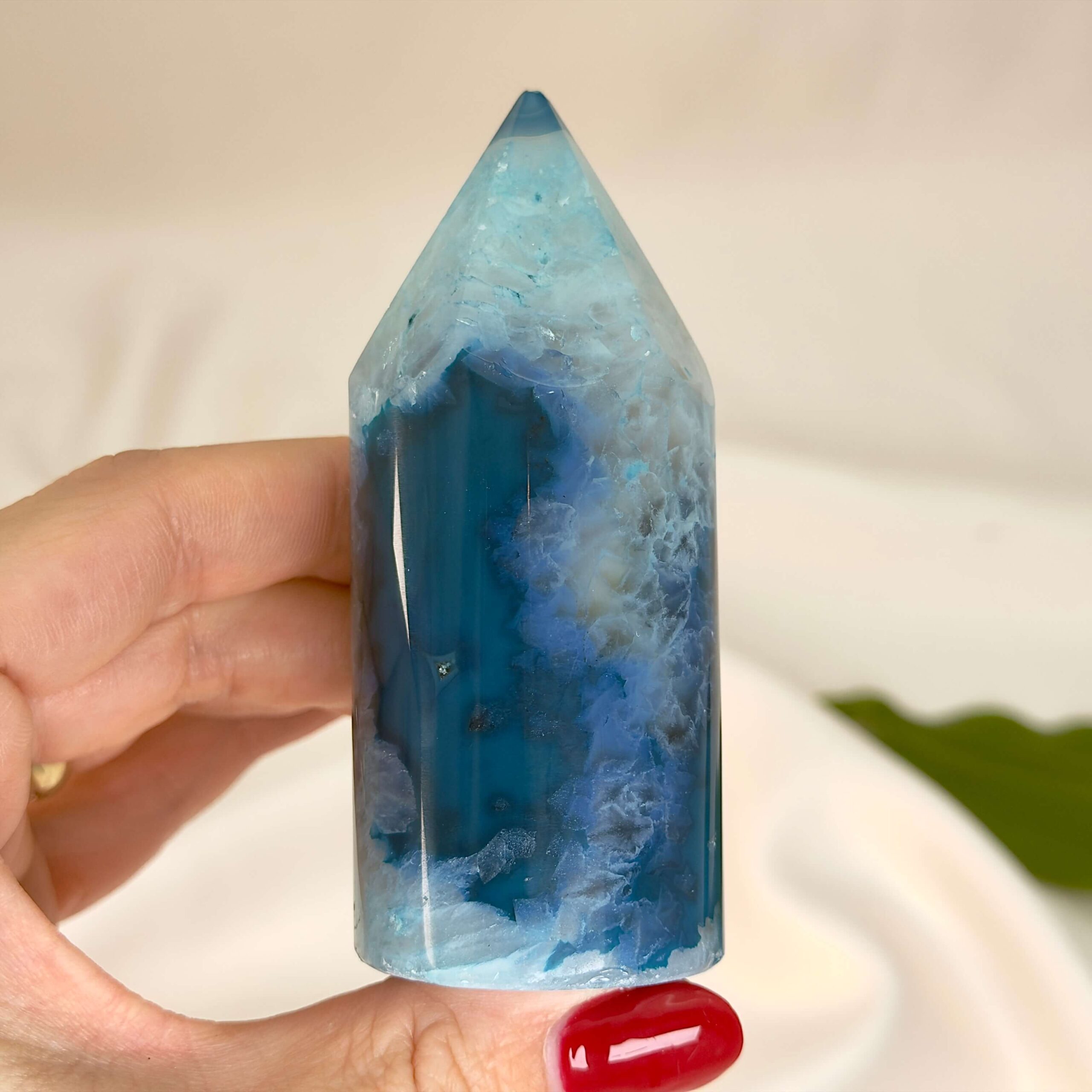 Agat blå krystal spids sten i hånd på hvid baggrund