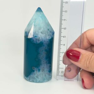 Agat blå krystal spids sten i hånd med lineal på hvid baggrund