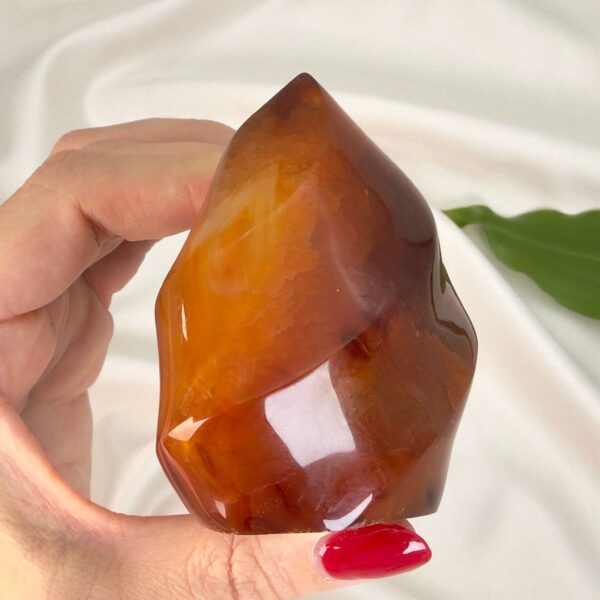 Karneol Freeform Flamme krystal sten i hånd på hvid baggrund