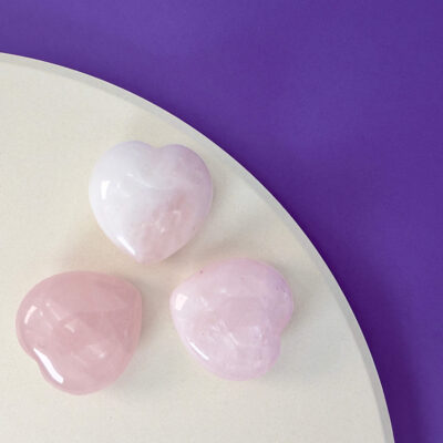 Rosakvarts Hjerte krystal sten på hvid og lilla baggrund