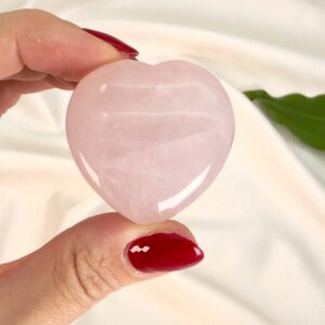Rosakvarts Hjerte krystal sten i hånd på hvid baggrund