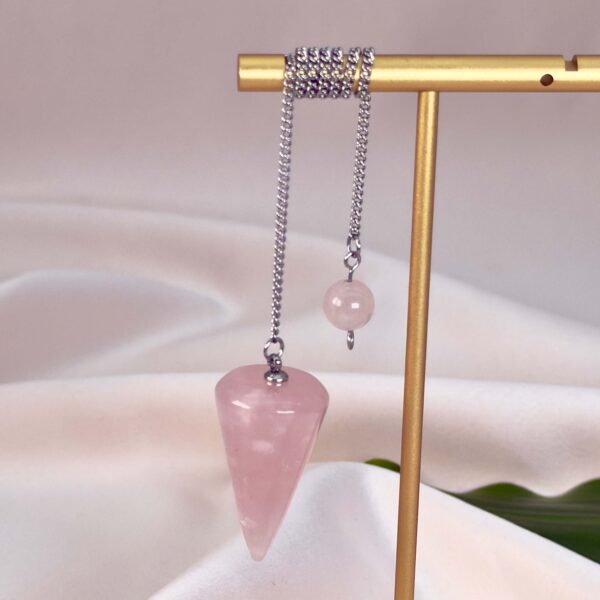 Rosakvarts pendul krystal sten på stativ på hvid baggrund