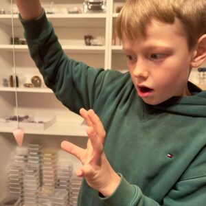 Rosakvarts pendul krystal sten i hånd på dreng Markus