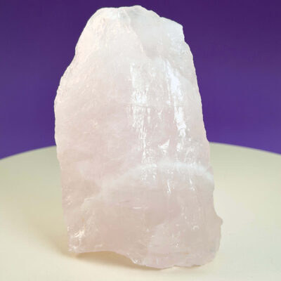 Rosakvarts Rå klynge krystal sten på hvid og lilla baggrund