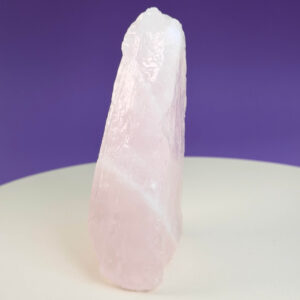 Rosakvarts Rå klynge krystal sten på hvid og lilla baggrund