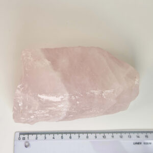 Rosakvarts Rå klynge krystal sten med lineal på hvid baggrund