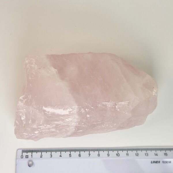 Rosakvarts Rå klynge krystal sten med lineal på hvid baggrund