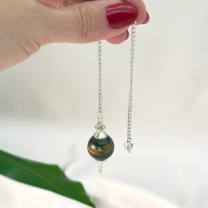 Tigerøje Pendul Krystal Sten med kæde i hånd på hvid baggrund