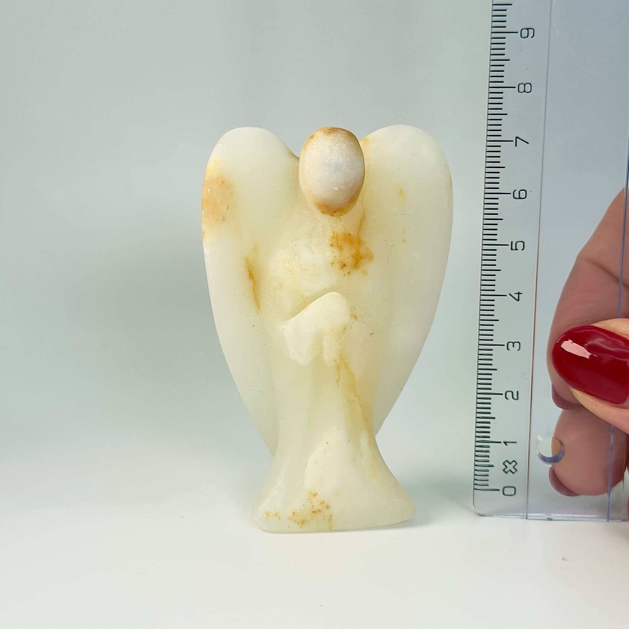 Pakistani Onyx Tårn krystal sten i hånd med lineal på hvid baggrund