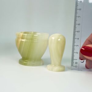 Pakistani Onyx Morter krystal sten i hånd med lineal på hvid baggrund