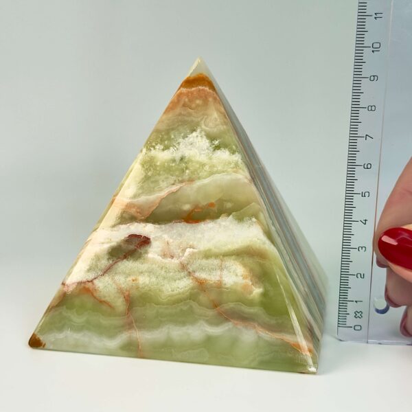 Pakistani Onyx Pyramide krystal sten i hånd med lineal på hvid baggrund
