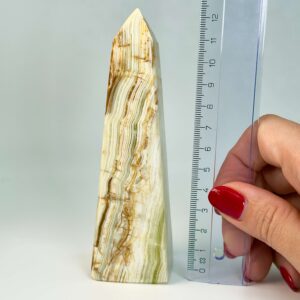 Pakistani Onyx Tårn krystal sten i hånd med lineal på hvid baggrund