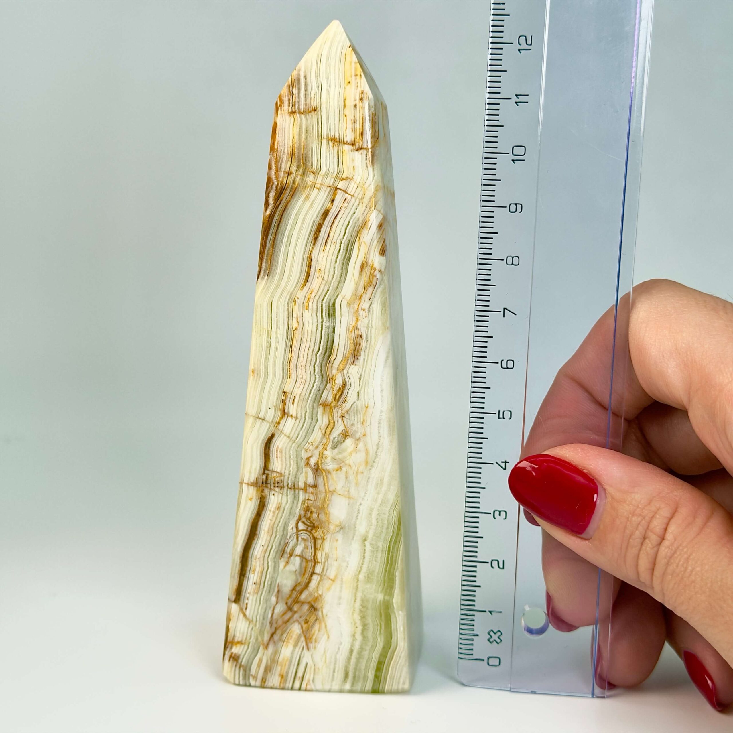 Pakistani Onyx Tårn krystal sten i hånd med lineal på hvid baggrund