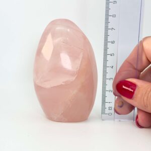 Rosakvarts Freeform Krystal Sten med lineal i hånd på hvid og lyserød baggrund