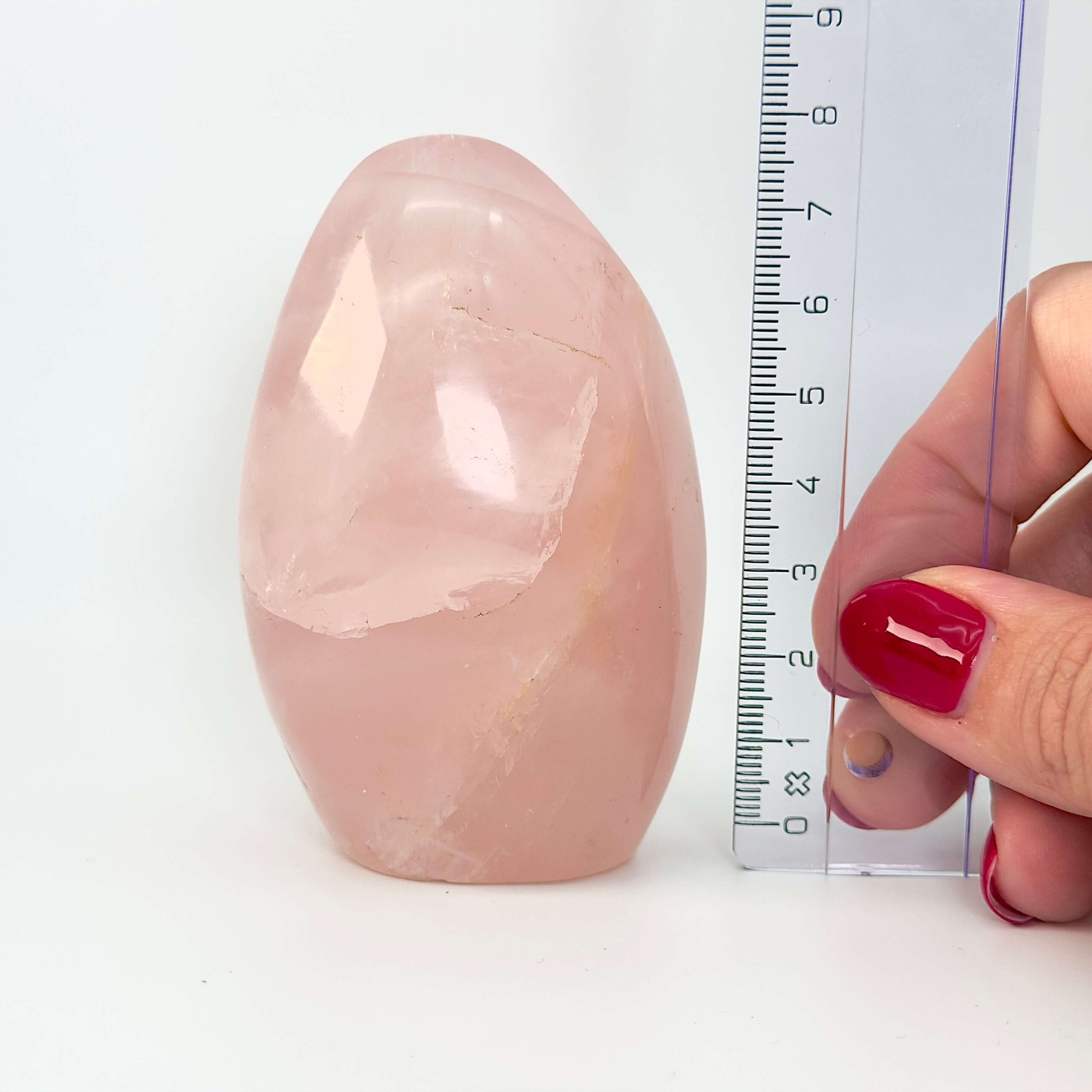 Rosakvarts Freeform Krystal Sten med lineal i hånd på hvid og lyserød baggrund