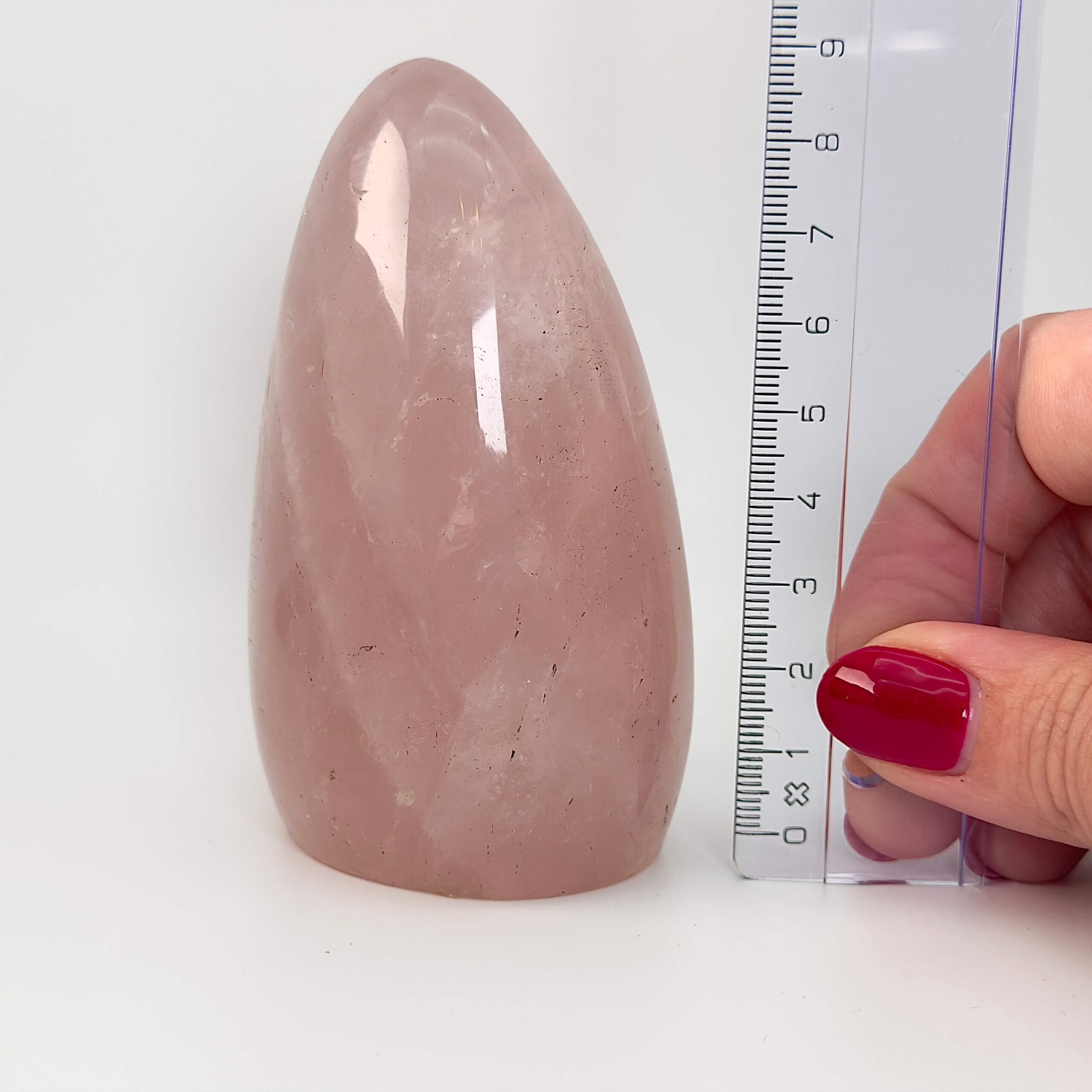 Rosakvarts Freeform Krystal Sten med lineal i hånd på hvid og lyserød baggrund