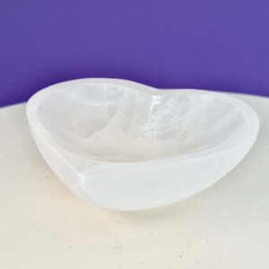 Selenit hjerte skål krystal sten 10 cm på hvid plade med lilla baggrund