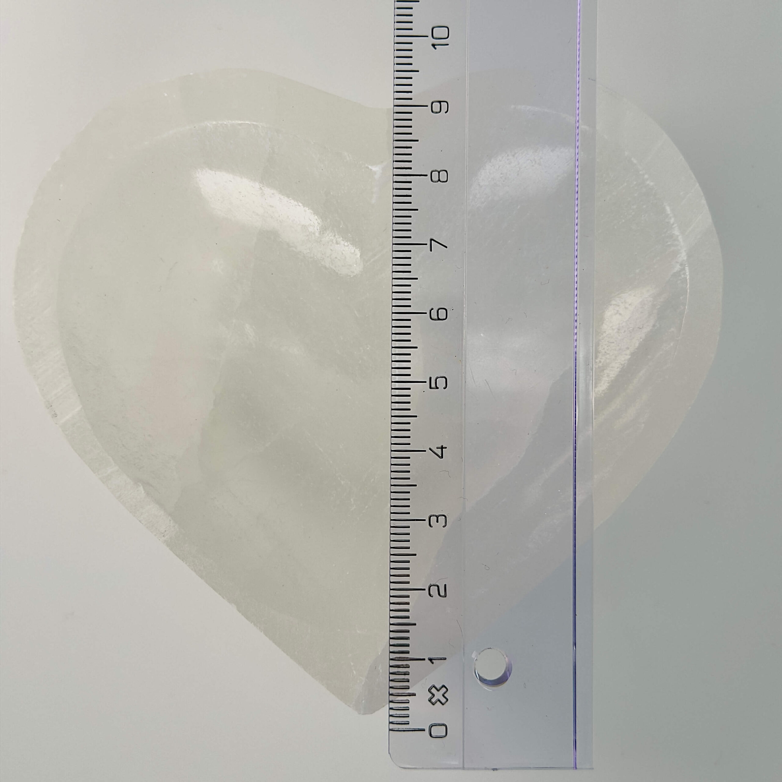 Selenit hjerte skål krystal sten 10 cm med lineal på hvid baggrund