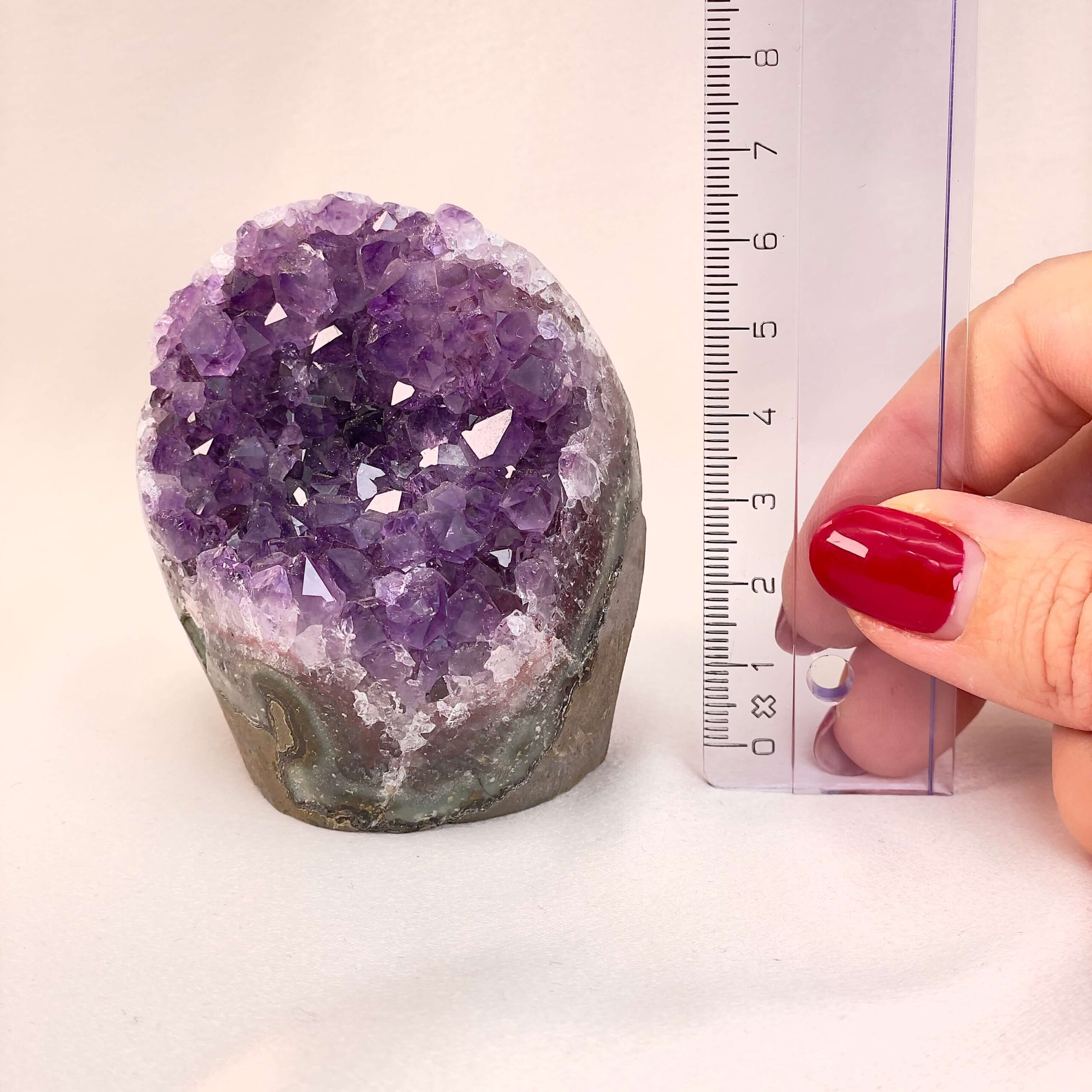 Ametyst Premium Grotte Krystal Sten med lineal i hånd på hvid baggrund