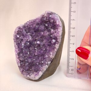 Ametyst Premium Grotte Krystal Sten med lineal i hånd på hvid baggrund