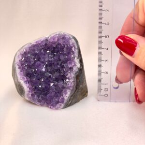 Ametyst Grotte Krystal Sten med lineal i hånd på hvid baggrund