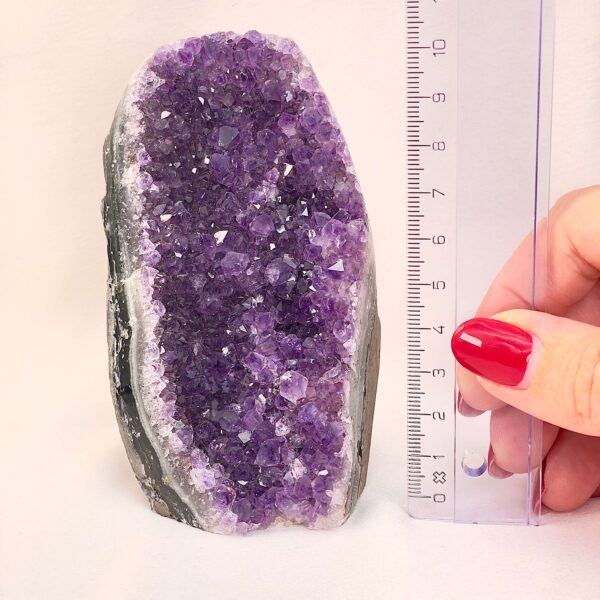Ametyst Premium Grotte Krystal Sten med lineal i hånd på hvid baggrund