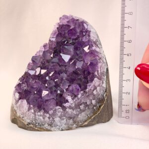 Ametyst Premium Grotte Krystal Sten med lineal i hånd på hvid baggrund
