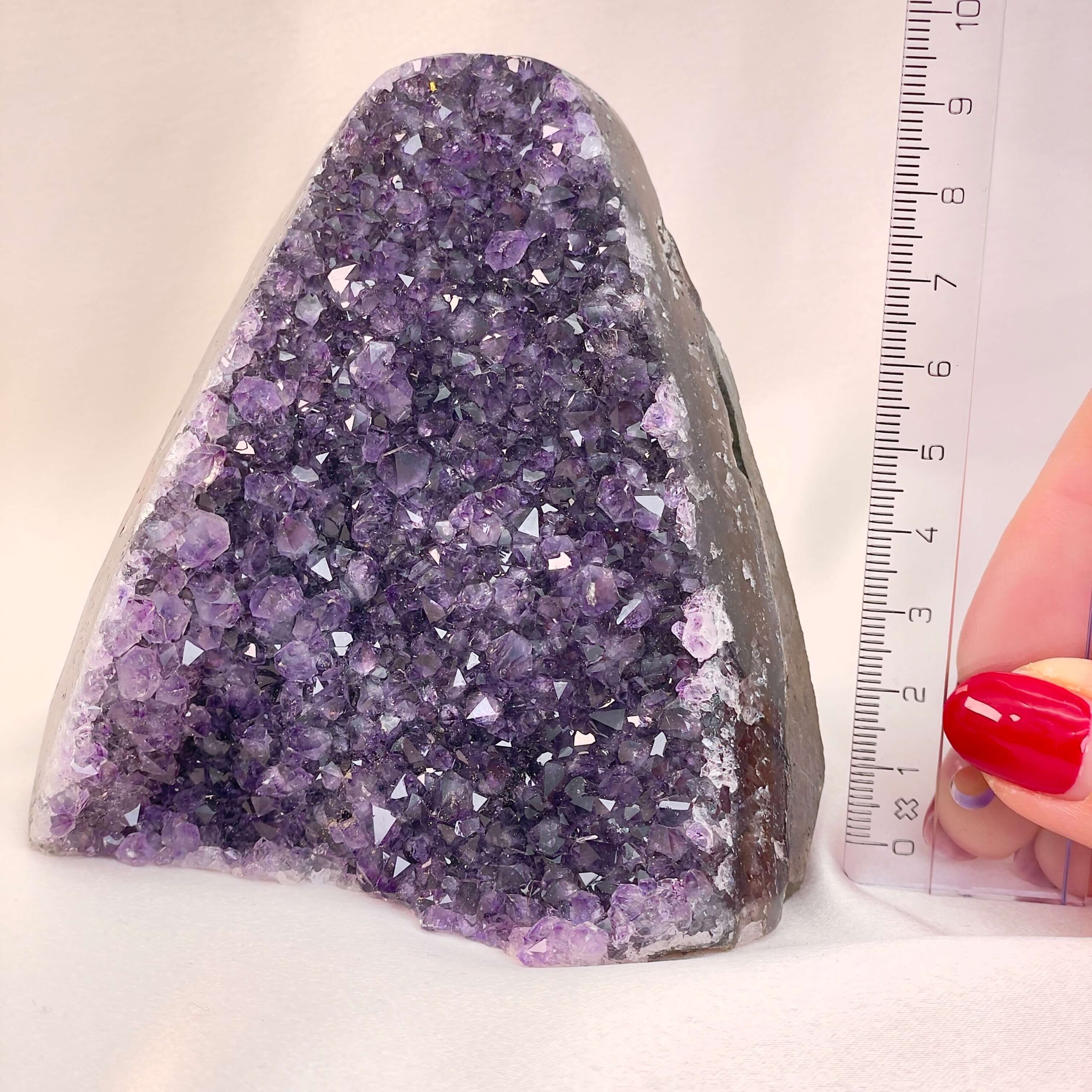 Ametyst Premium Grotte Krystal Sten med lineal i hånd på hvid baggrund