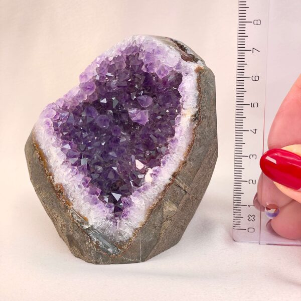Ametyst Premium Grotte Krystal Sten med lineal i hånd på hvid baggrund