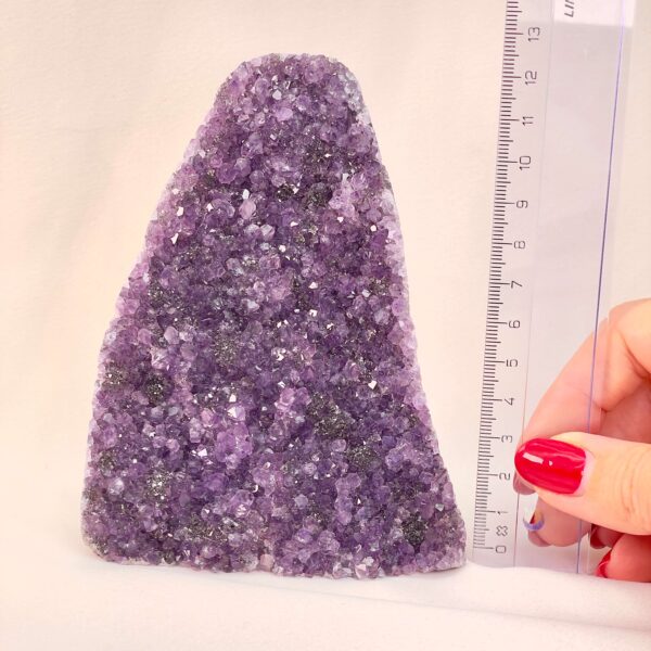 Ametyst Premium Grotte Krystal Sten med lineal i hånd på hvid baggrund