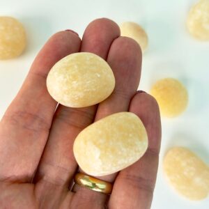 Calsit Gul Lommesten Krystal Sten i hånd på hvid baggrund