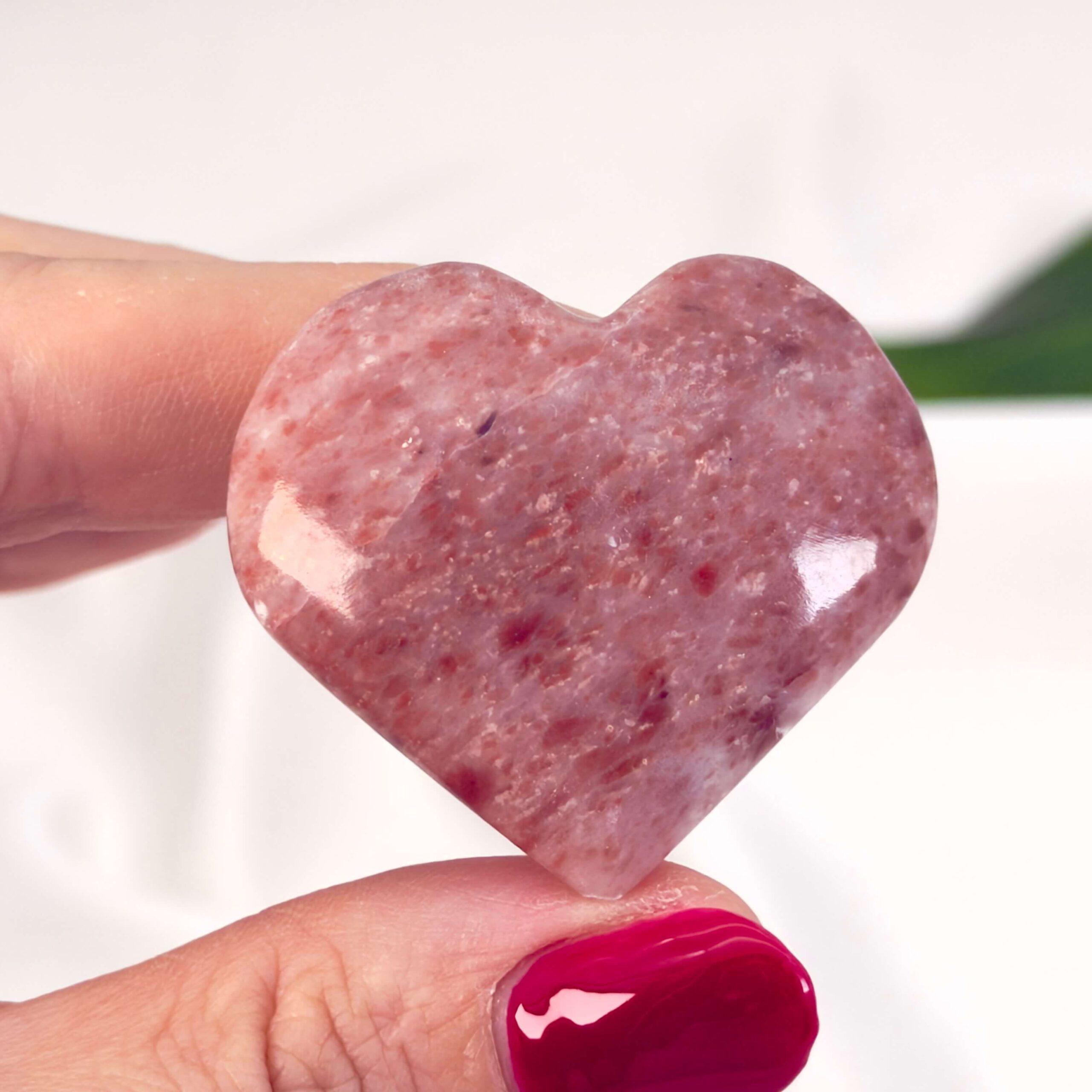 Jordbær Calsit Hjerte Krystal Sten i Hånd på hvid baggrund