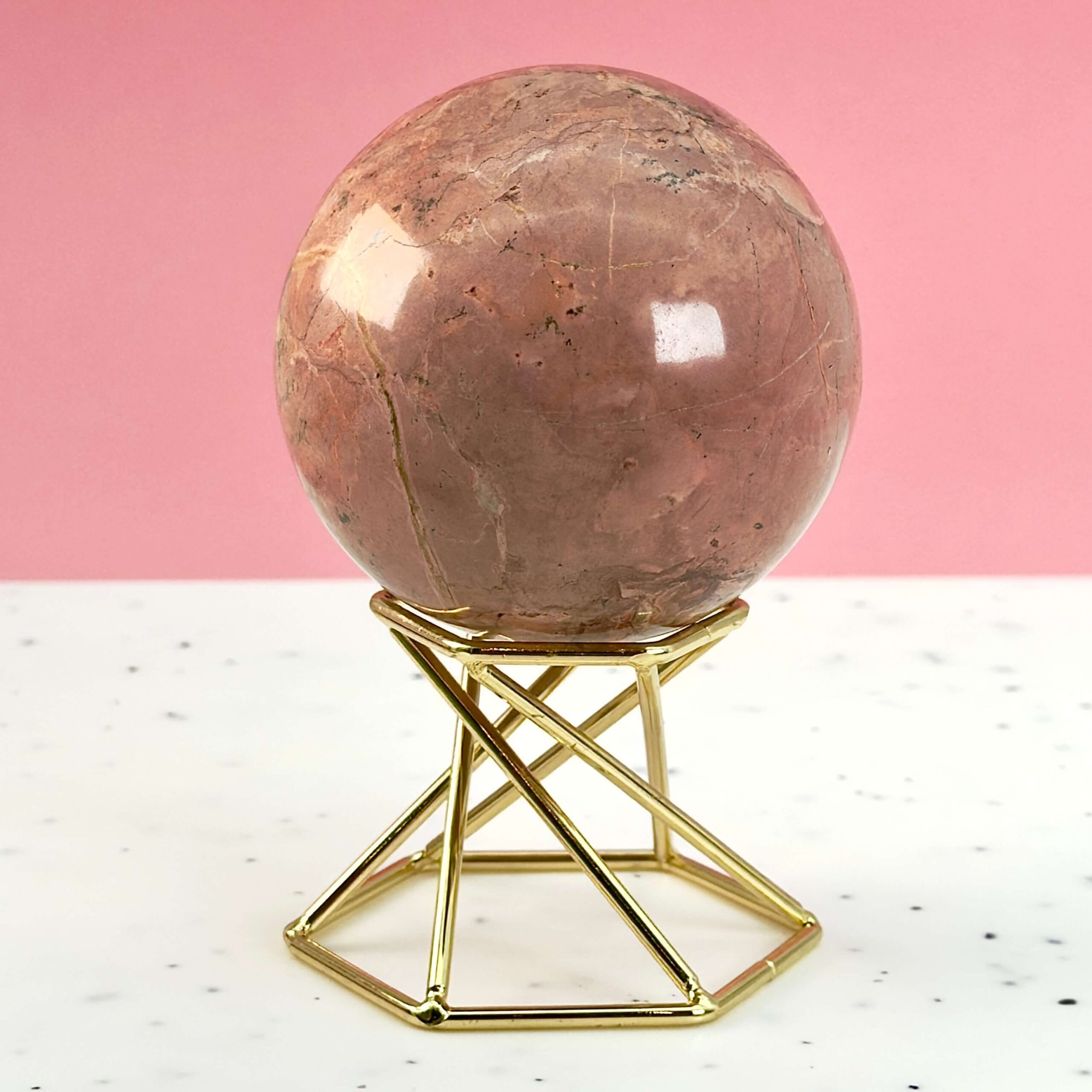 Jordbær Calsit Kugle Krystal Sten på hvid og lyserød baggrund