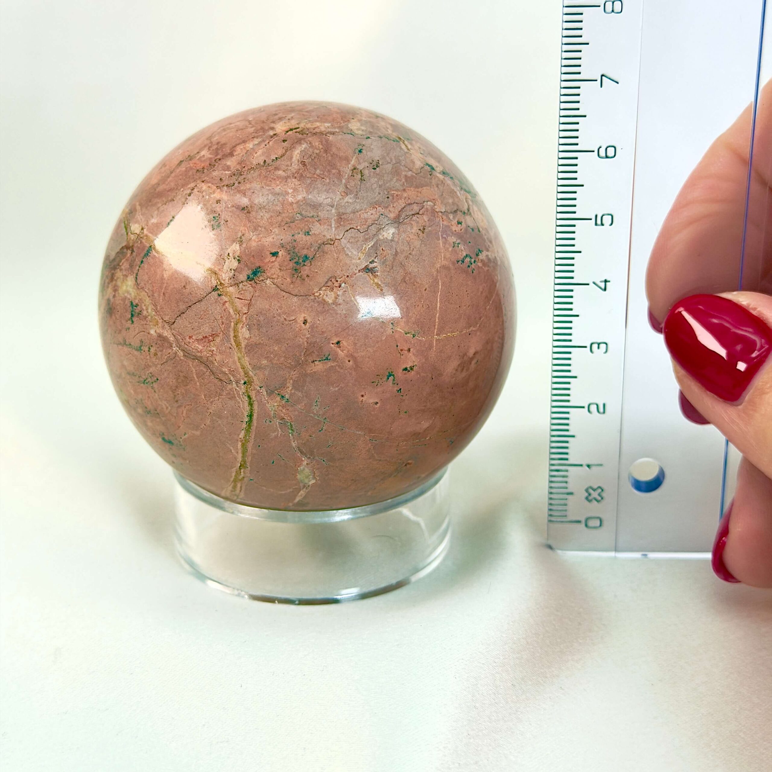 Jordbær Calsit Kugle Krystal Sten med lineal på hvid baggrund