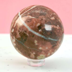 Jordbær Calsit Kugle Krystal Sten på hvid og lyserød baggrund