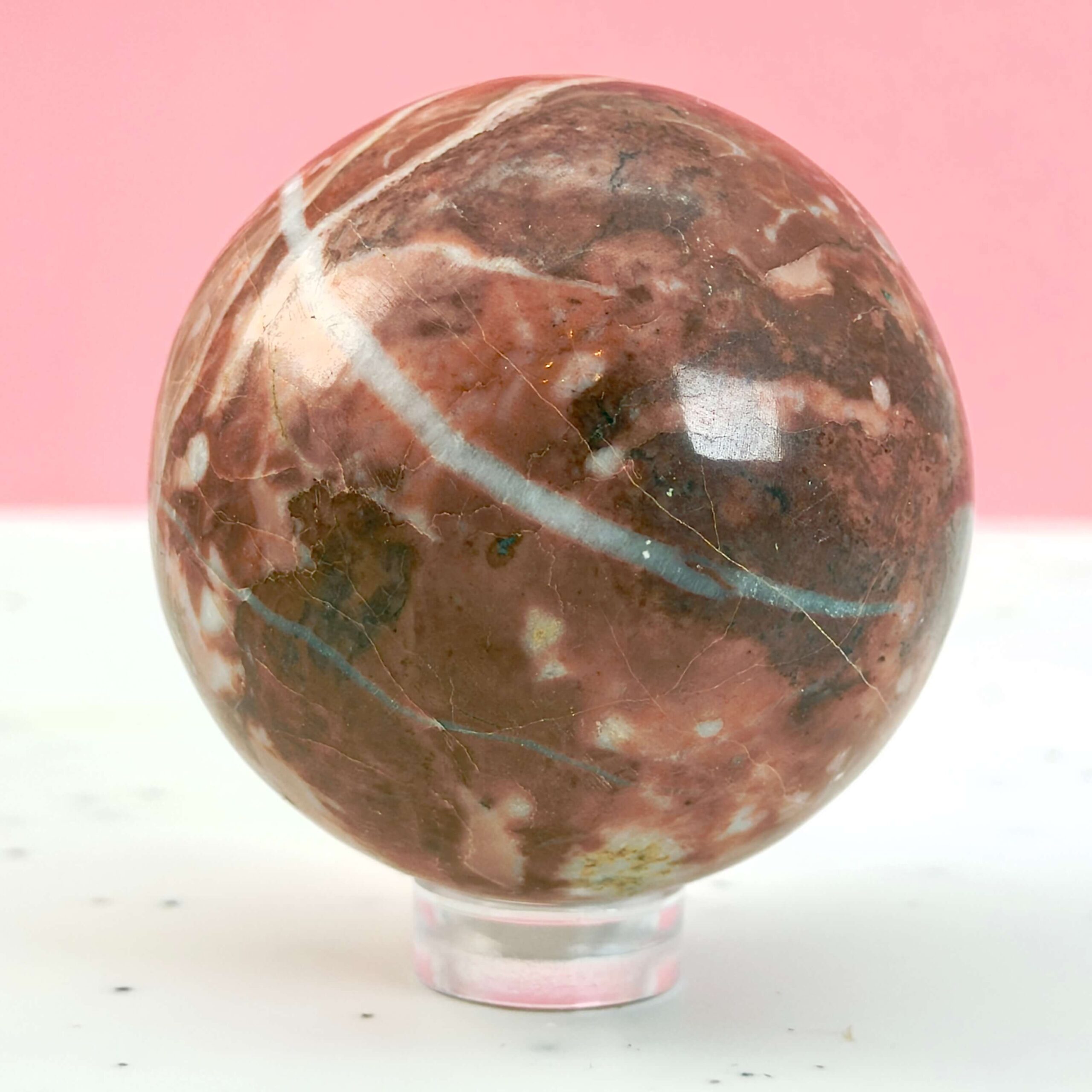 Jordbær Calsit Kugle Krystal Sten på hvid og lyserød baggrund