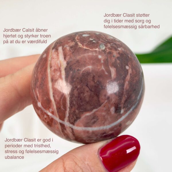 Jordbær Calsit Kugle Krystal Sten i hånd på hvid baggrund med tags