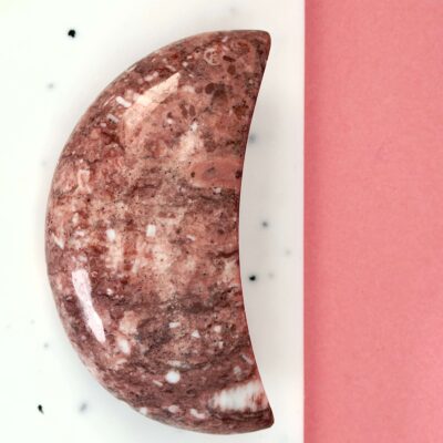 Jordbær Calsit Måne Krystal Sten på hvid og lyserød baggrund