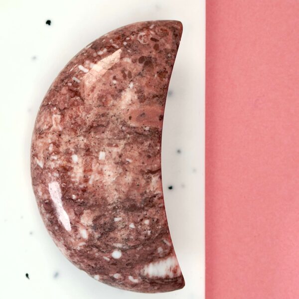 Jordbær Calsit Måne Krystal Sten på hvid og lyserød baggrund