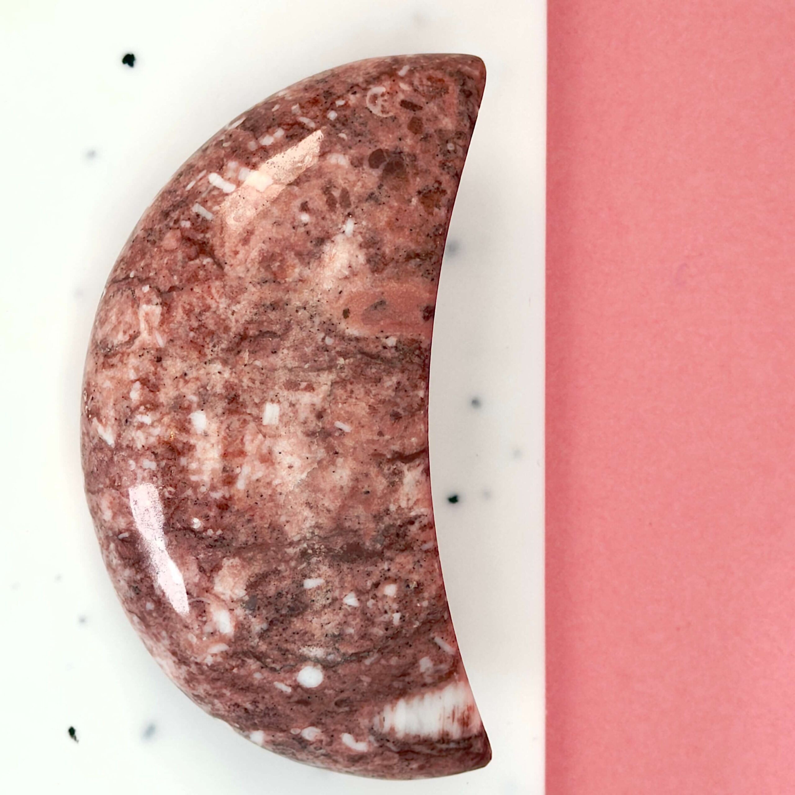 Jordbær Calsit Måne Krystal Sten på hvid og lyserød baggrund