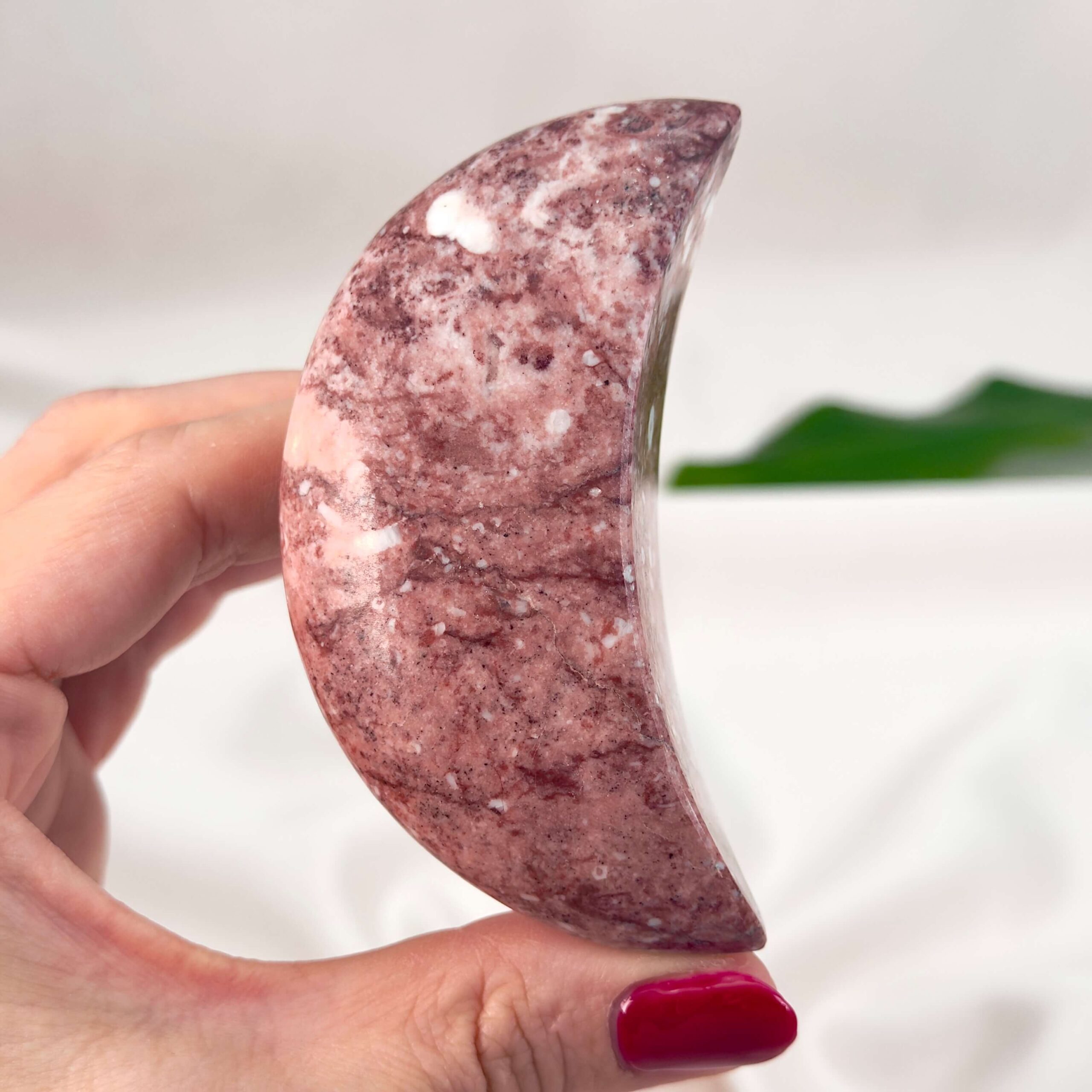 Jordbær Calsit Måne Krystal Sten i hånd på hvid baggrund