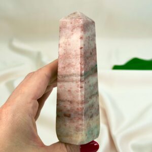 Jordbær Calsit Tårn Krystal Sten i hånd på hvid baggrund