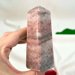 Jordbær Calsit Tårn Krystal Sten i hånd på hvid baggrund