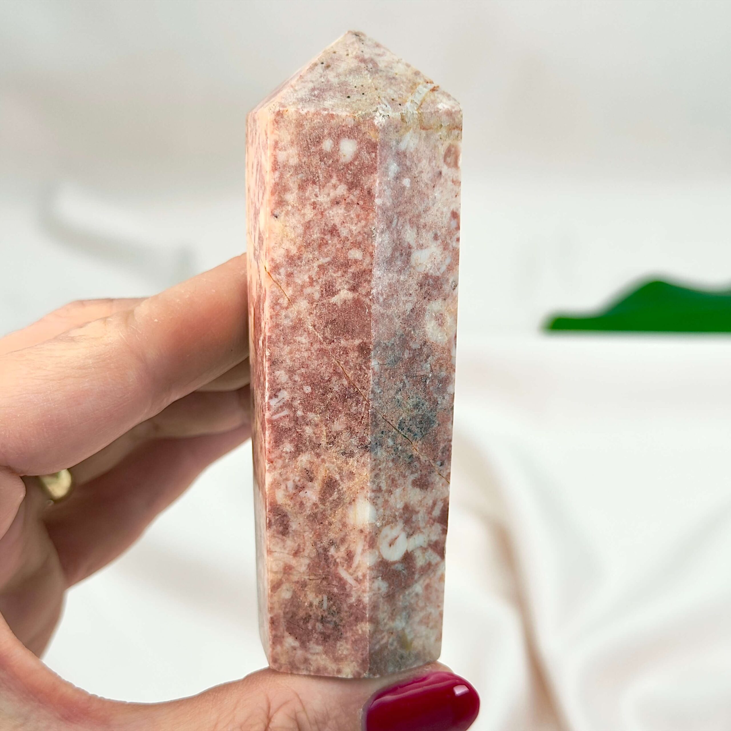 Jordbær Calsit Tårn Krystal Sten i hånd på hvid baggrund