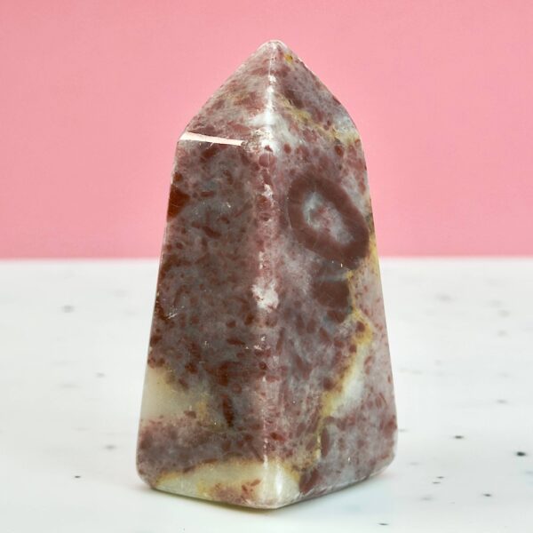 Jordbær Calsit Tårn Krystal Sten på hvid og lyserød baggrund