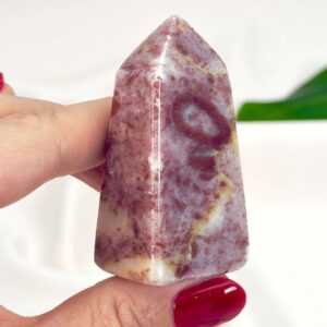 Jordbær Calsit Tårn Krystal Sten i hånd på hvid baggrund