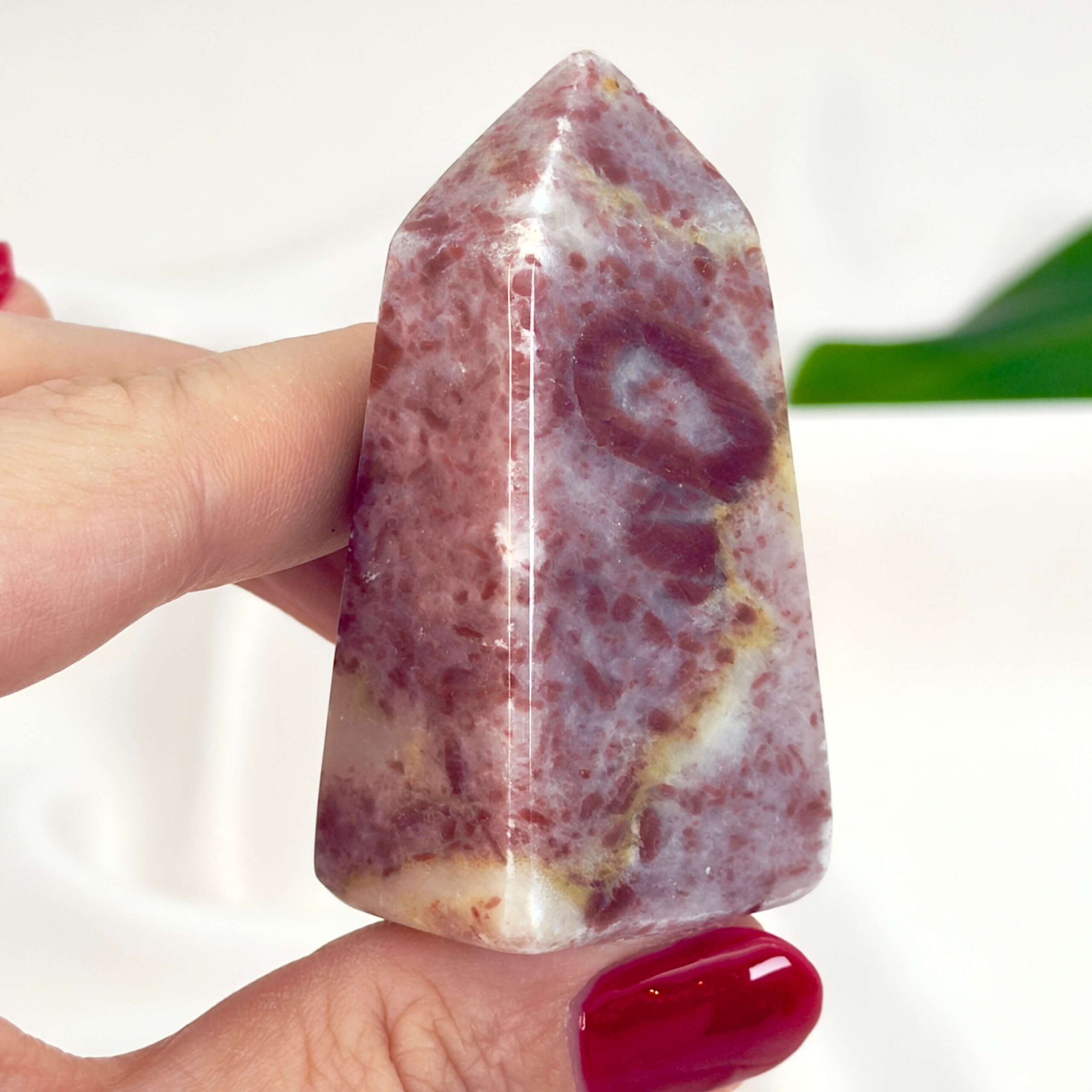 Jordbær Calsit Tårn Krystal Sten i hånd på hvid baggrund