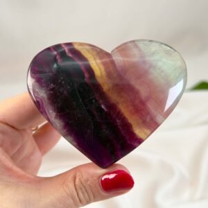 Fluorit Regnbue Hjerte Krystal Sten med hånd på hvid baggrund