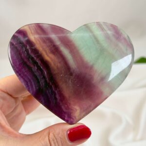 Fluorit Regnbue Hjerte Krystal Sten med hånd på hvid baggrund