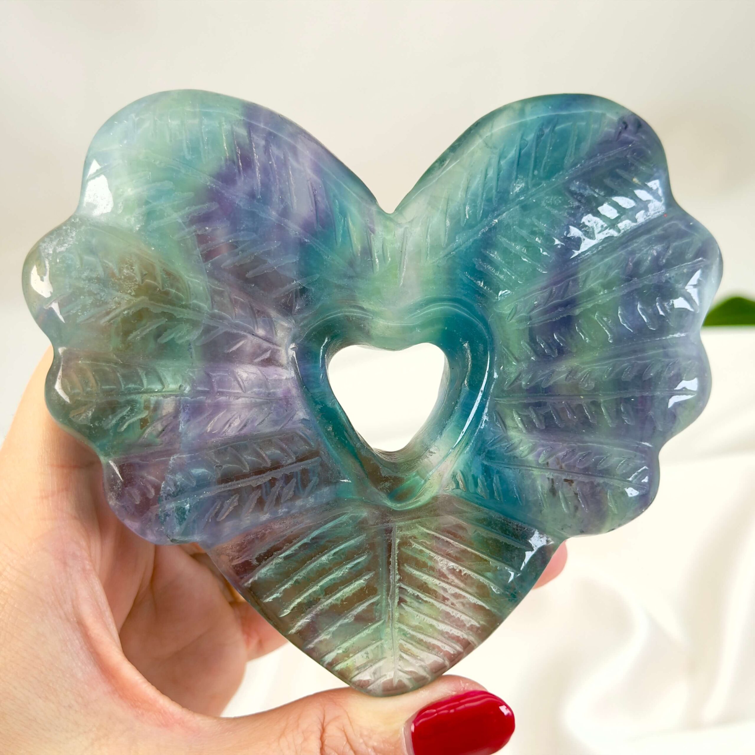 Fluorit Regnbue Hjerte krystal sten i hånd på hvid baggrund